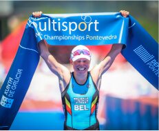 Alexandra Tondeur brandit la banderole d'arrivée des Multisport Championships de Pontevedra, maillot belge.